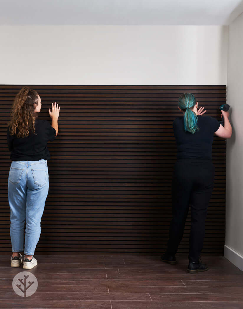 Installation of smoked oak acoustic slat wall panels for rustic interior wall panelling.