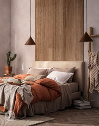 Modern bedroom with Oak Ridge Flexible Tambour Wood Panels as luxury wall panels behind a cozy bed, warm lighting, and stylish decor.
