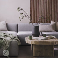 Modern living room with gray sofa and Walnut Ridge tambour wood panel accent wall, featuring a wooden coffee table and decorative vase.