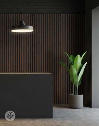 Smoked oak acoustic slat wood wall panels in a stylish interior with modern lighting and green plant, showcasing rustic wall panelling.