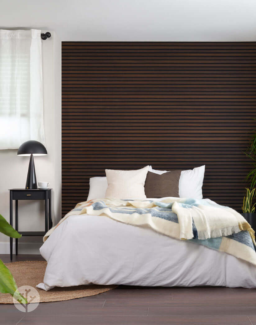 Bedroom with smoked oak acoustic slat wall panels and cozy bedding, showcasing stylish interior wall panelling.