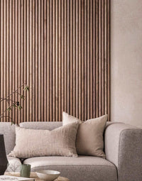 Luxury wall panels in walnut finish add elegance to modern living room with gray sofa and neutral decor.