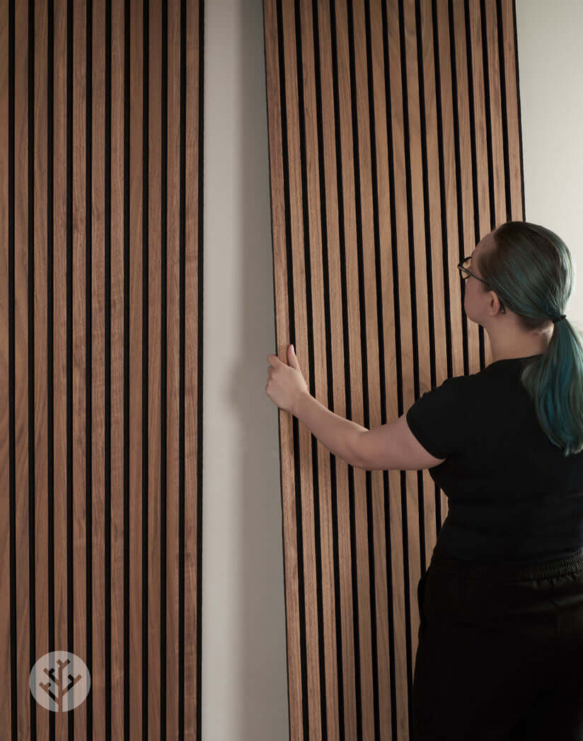 Person installing Natural Walnut Acoustic Slat Wall Panels for improved interior acoustics and elegance.
