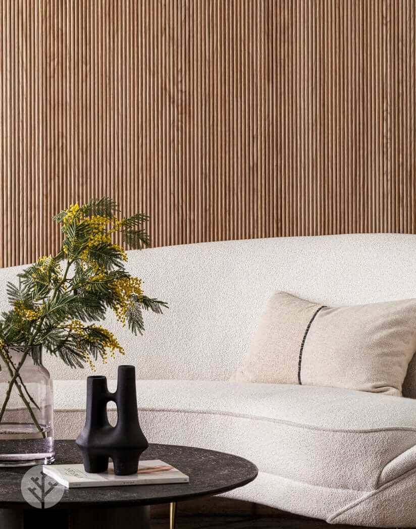 Luxury living room with Oak Mini-Ridge Flexible Tambour Wood Panels adding warmth and elegance to the wall behind a modern sofa and decor.