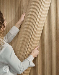Person installing oak mini-ridge flexible tambour wood panels, showcasing luxury wall design for interiors.