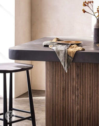 Walnut Mini-Ridge flexible tambour wood panel on a modern kitchen island with a black stool and decorative items.