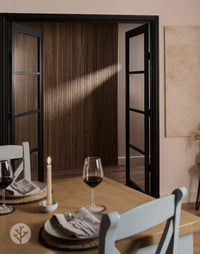 Dining room featuring Walnut Ridge Flexible Tambour luxury wall panels and elegant table setting with wine glasses.