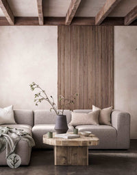 Luxury interior with Walnut Ridge Flexible Tambour Wood Panels on wall, featuring modern sofa and wooden coffee table.