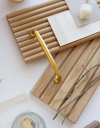 Flexible tambour wood panels sample box with a gold handle and natural decor items on a light background.