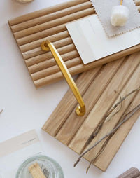 Flexible tambour wood panels sample box with a gold handle and natural decor items on a light background.