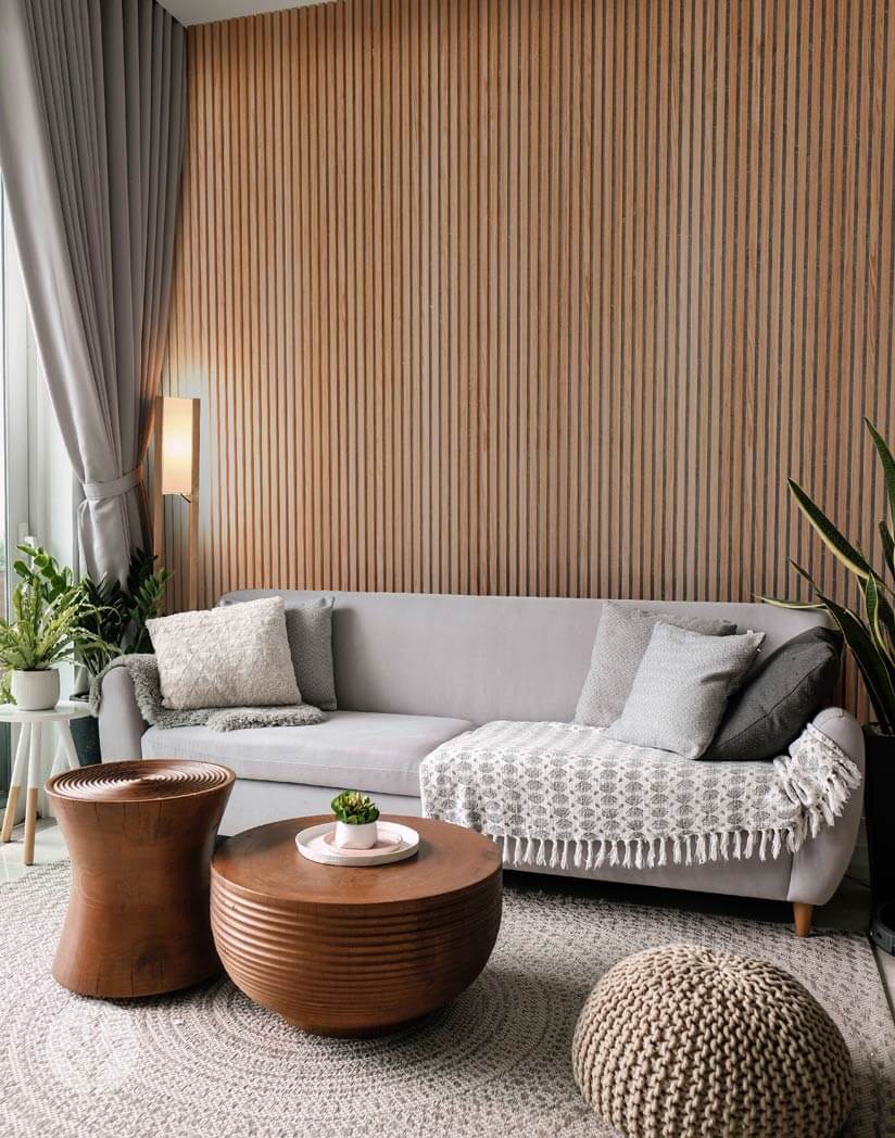 Elegant living room with oak slat wall panels, grey sofa, and decorative cushions, enhancing interior style and acoustic quality.